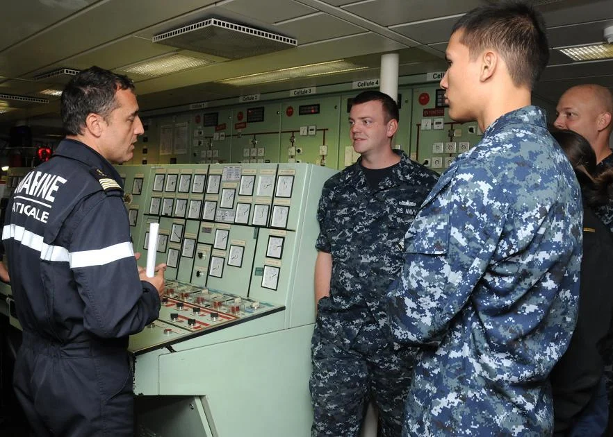 Le capitaine de frégate Renaud Bondil, commandant du Prairial, présente la salle des machines à des marins du croiseur USS Chosin