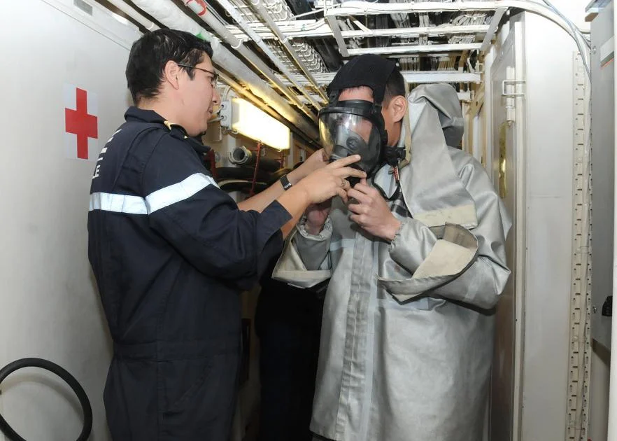 Le second-maître Manuel Dufourquet aide un marin américain à revêtir la combinaison de pompier