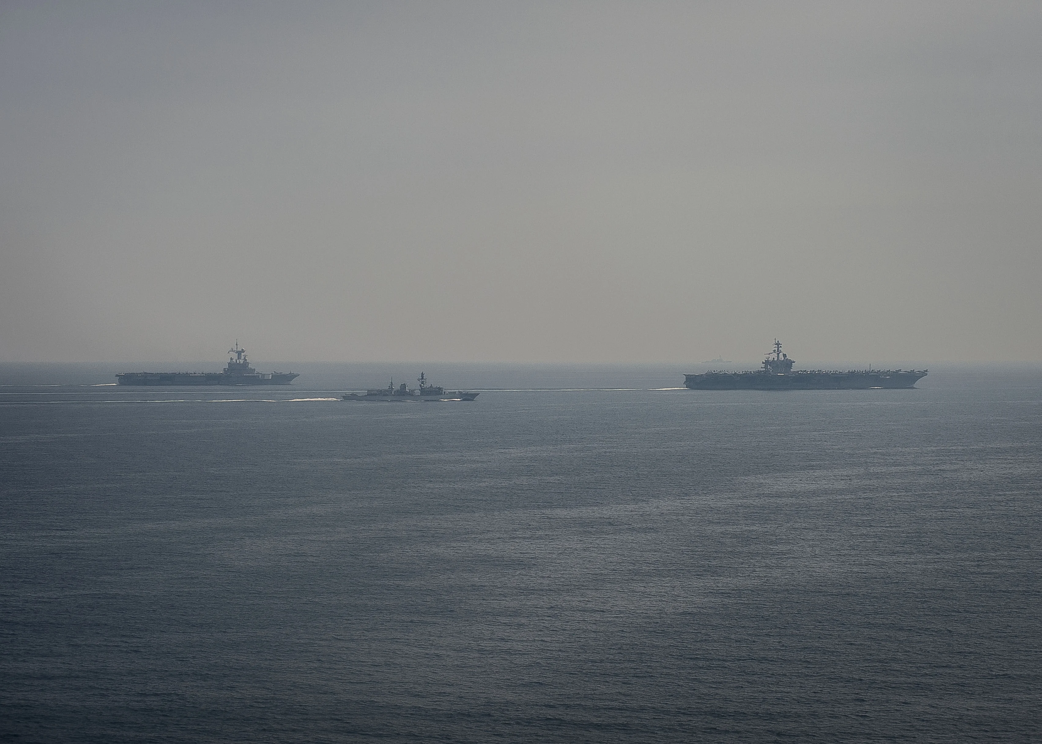 Le porte-avions Charles de Gaulle (à gauche), la frégate britannique HMS Kent (au centre), et le porte-avions américain USS Carl Vinson (à droite) naviguent en formation dans le golfe Persique