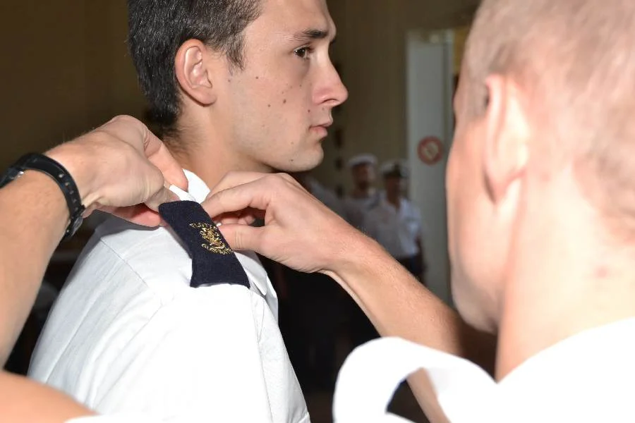 Un élève en première année d’études supérieures au Lycée Naval reçoit d'un de ses ainés le manchon « Flotte Guépratte »