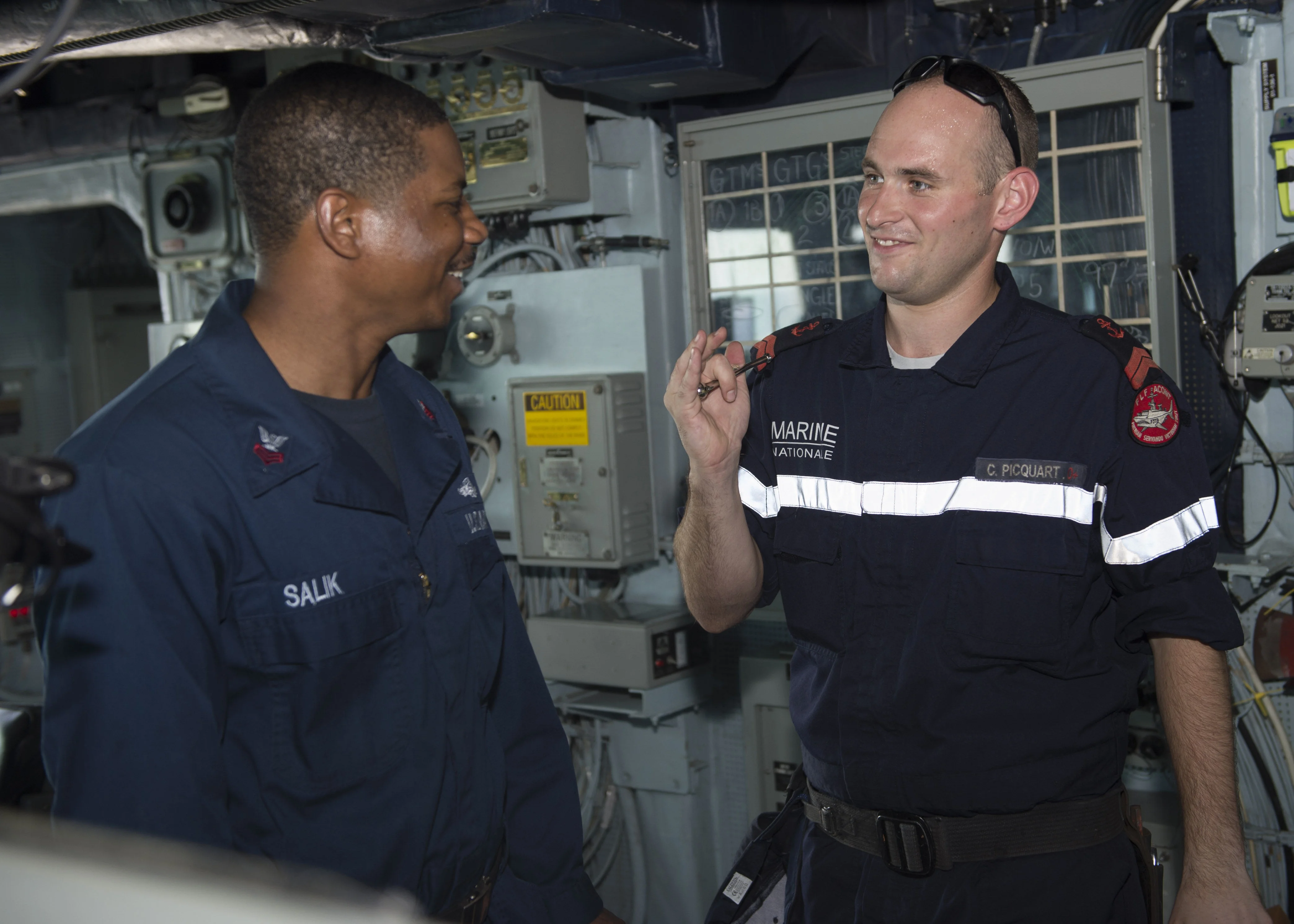 Le manoeuvrier de 1ère classe Antoine Salik, du destroyer USS Bulkeley, partage des techniques de sifflet avec le quartier-maître de 2è classe Clément Picquart, de la frégate Aconit