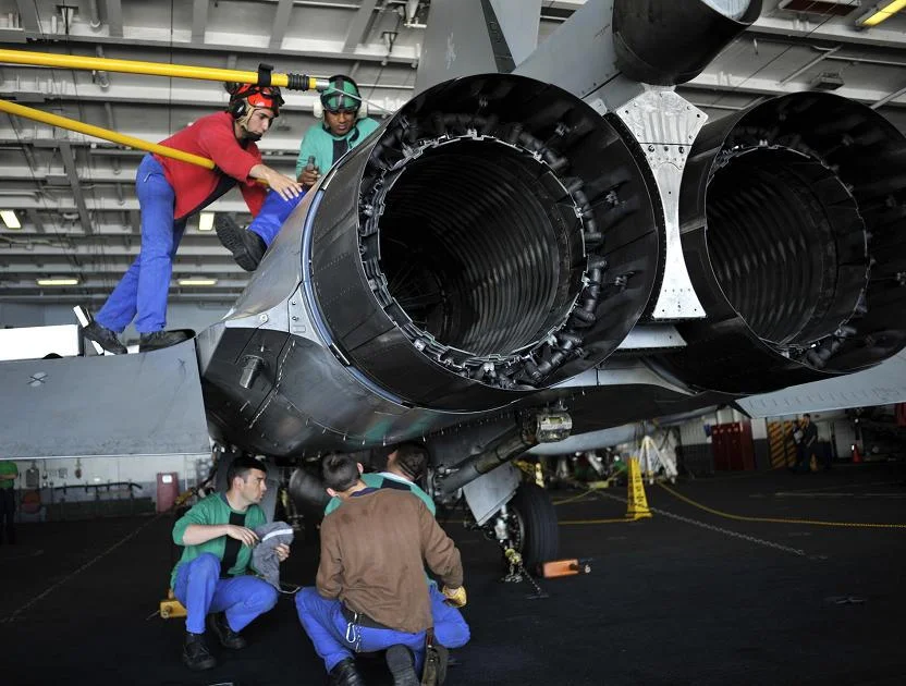 Une équipe de maintenance de la marine nationale, appartenant à l'escadrille 12F de Rafale, effectue un échange de moteur à bord du porte-avions américain USS Harry S. Truman