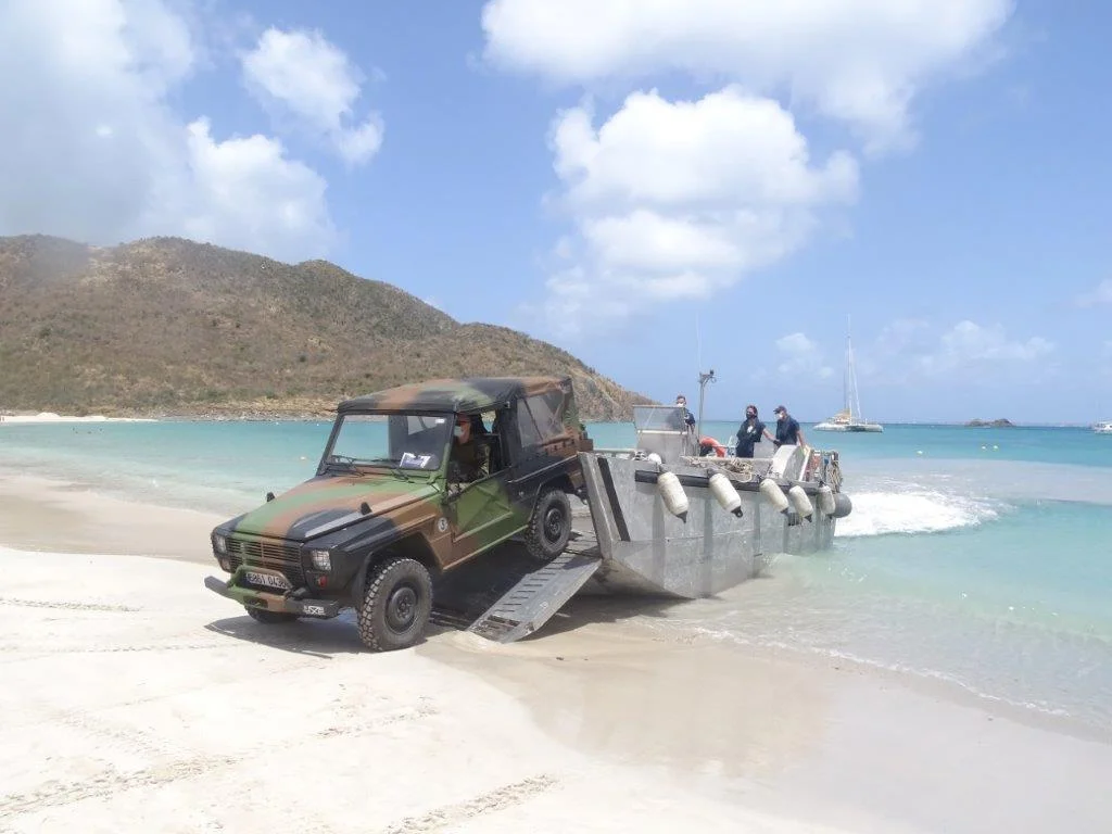 Une embarcation de servitude du Dumont d'Urville débarque un P4 sur une plage